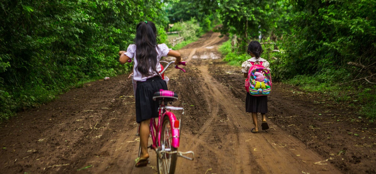 Little girl biking to school and little girl walking to school