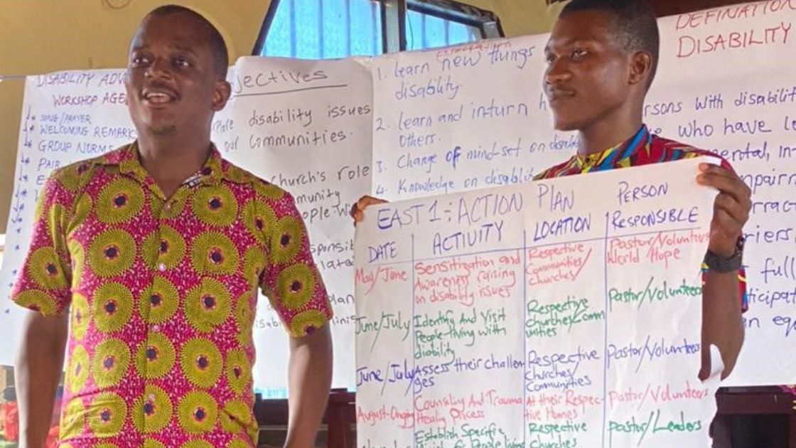 Two men display their pastoral action plan for ministering to the disabled