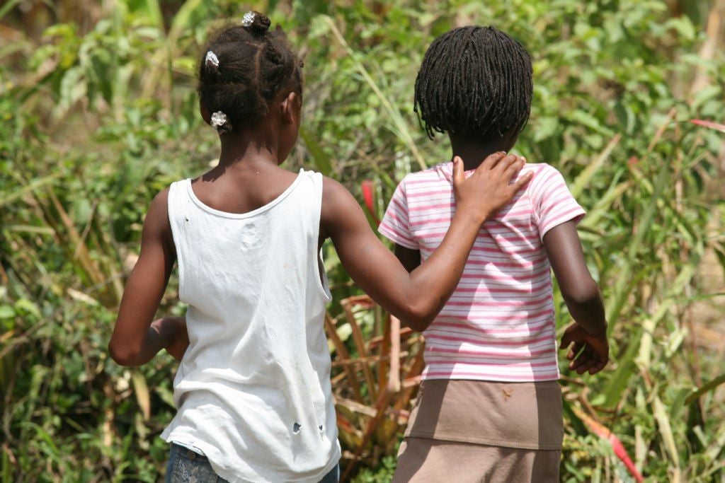 2 Haitian Girls, one with her arm around the other