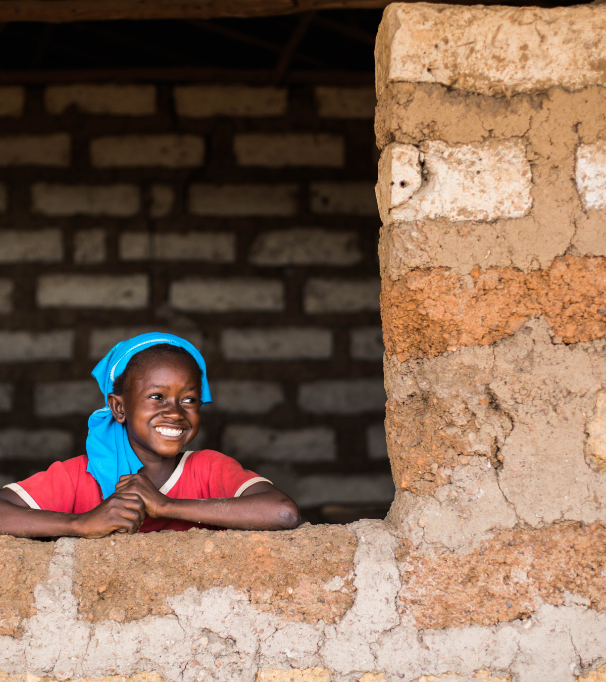 Smiling child looking out over a brick wall