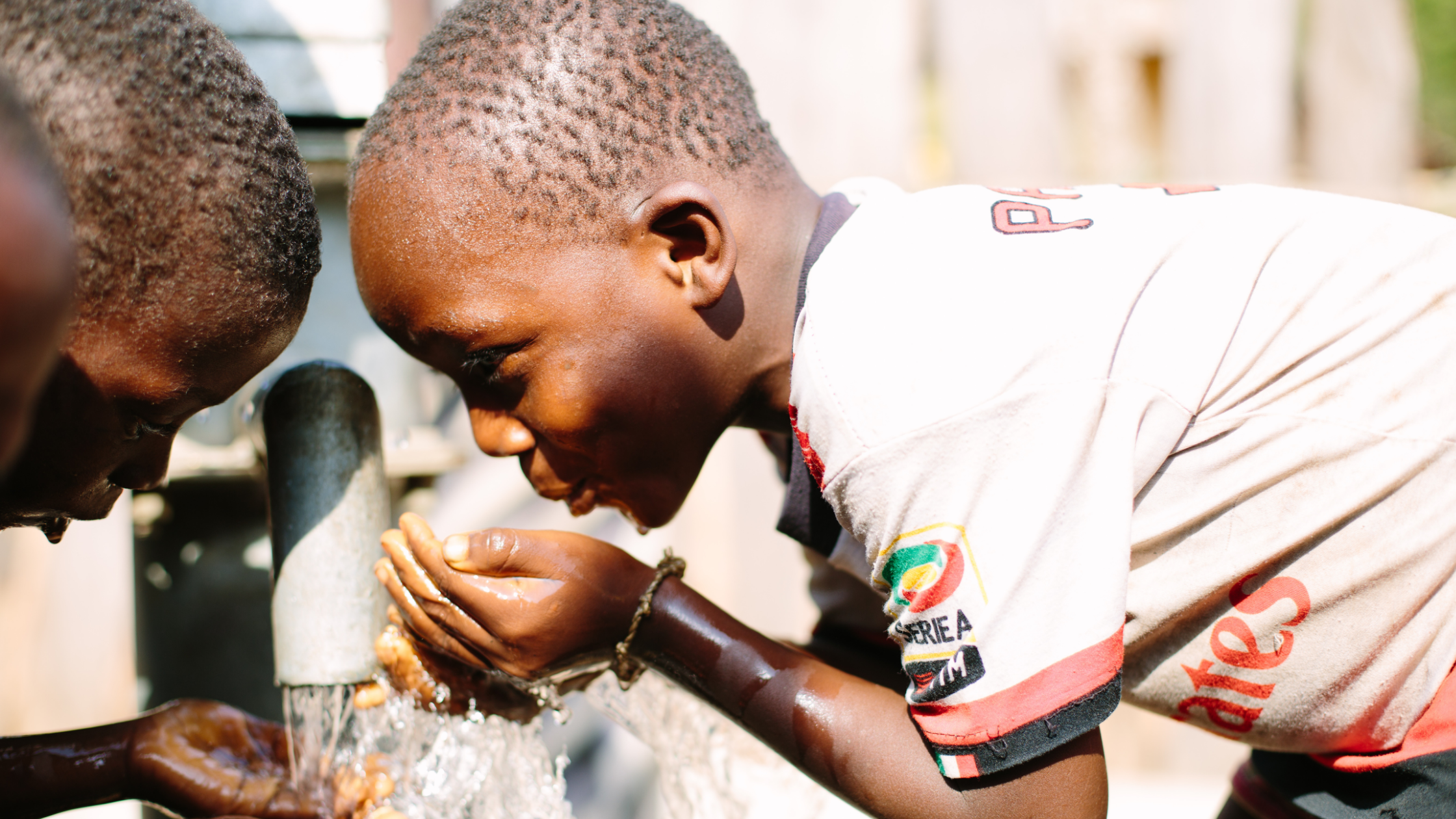 Boys drinking water from clean waterpoint