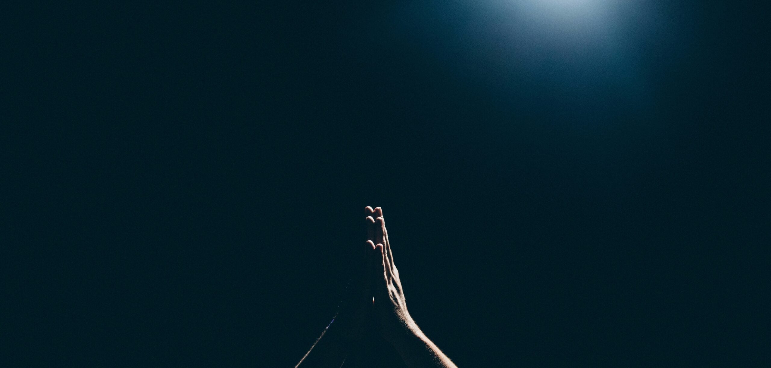 hands lifted in prayer on dark background