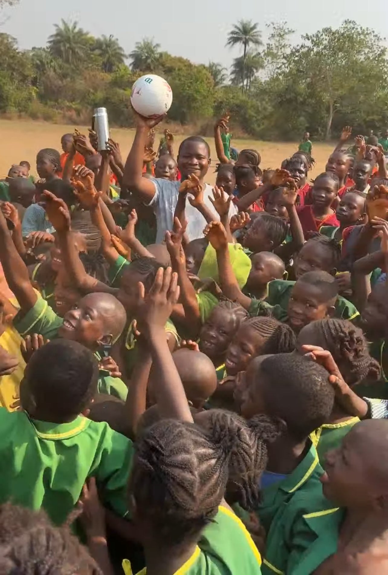 man with soccer ball surrounded by children