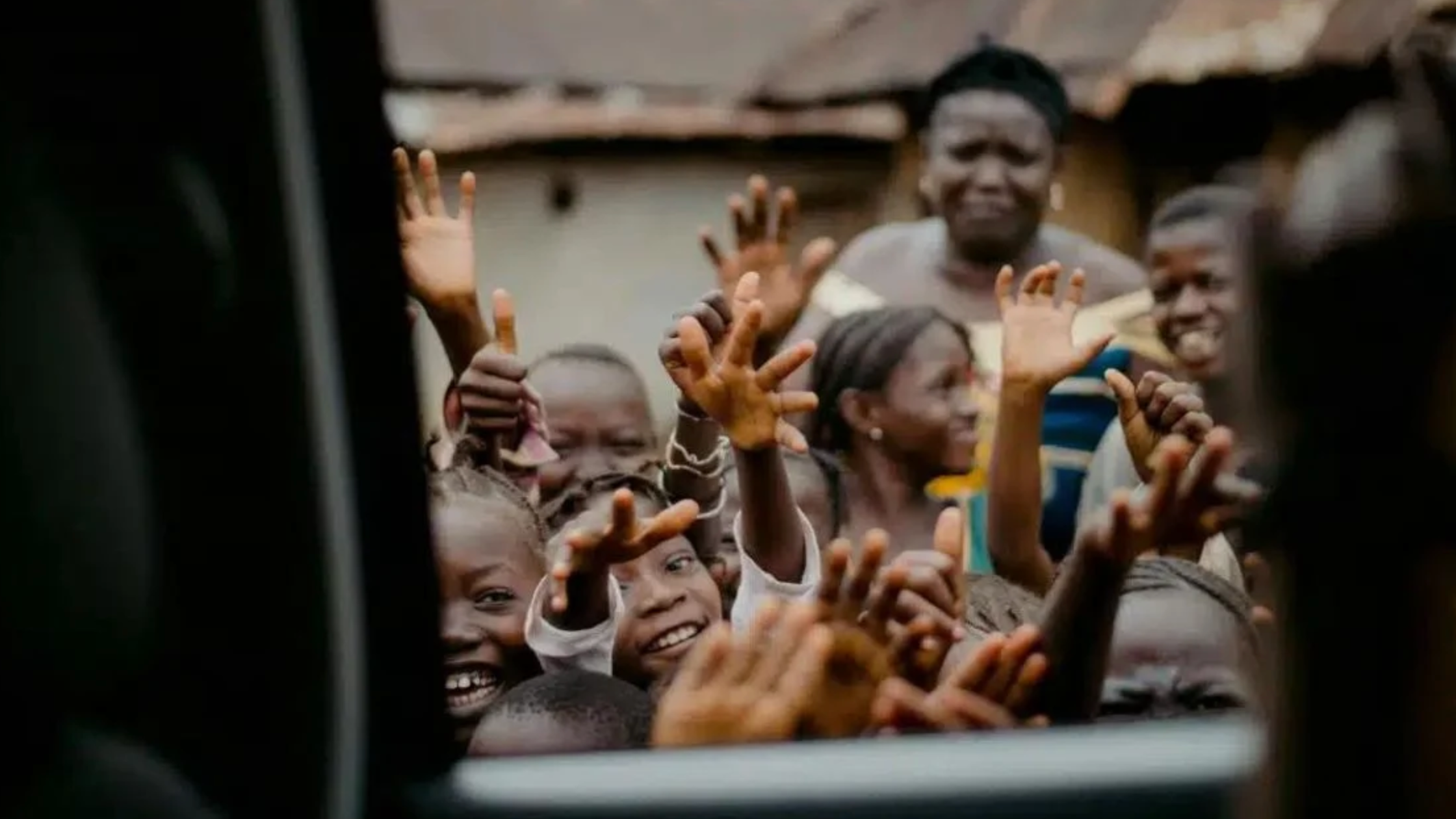 children with hands in the air through a car window