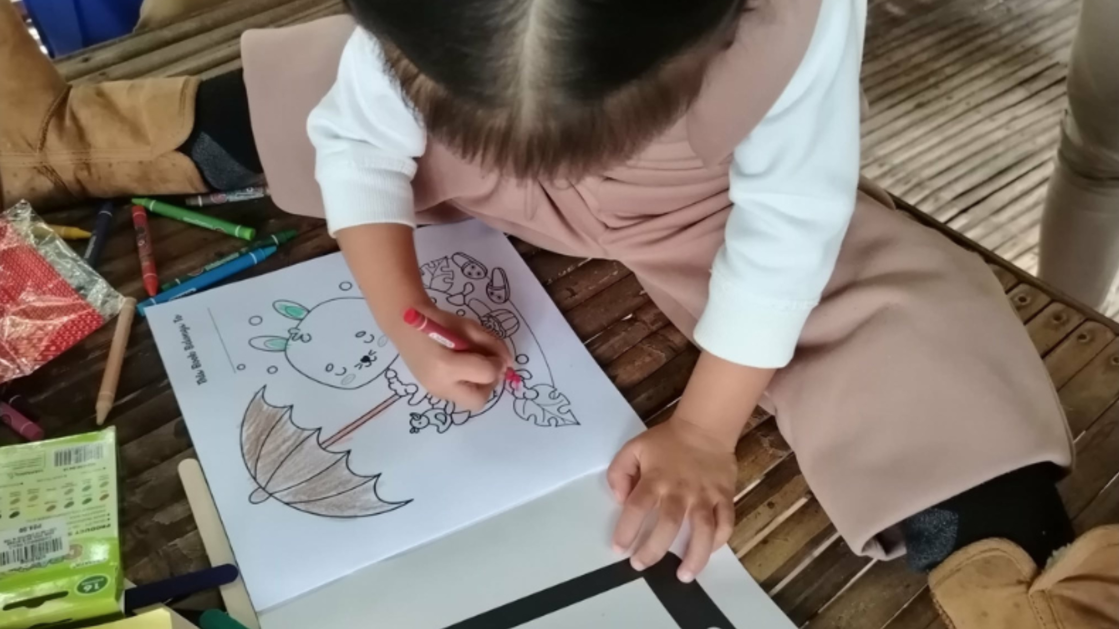 Gene, a survivor of online exploitation and abuse, sitting on the floor colouring.