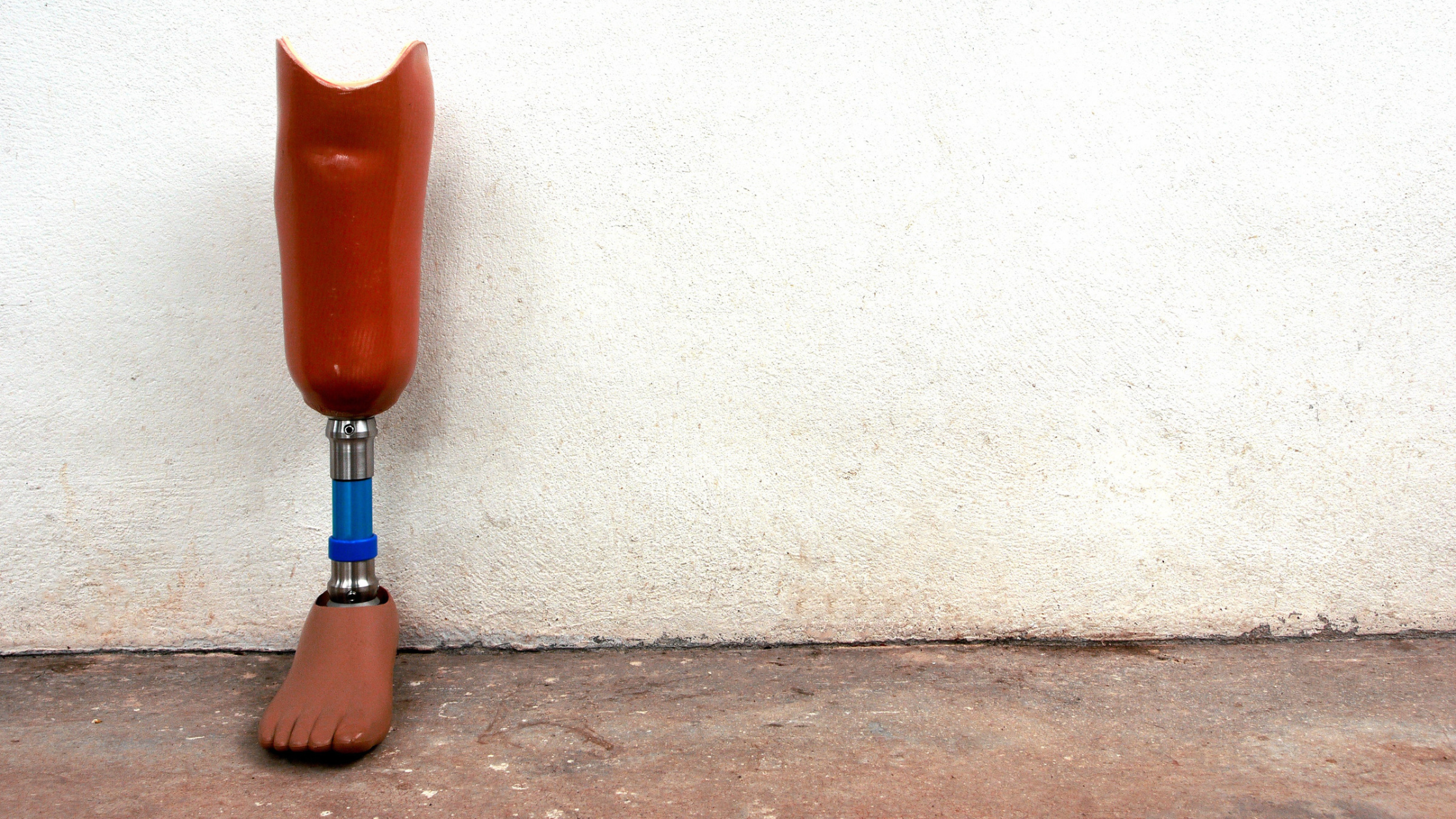 A prosthetic leg leaning against a stucco wall.